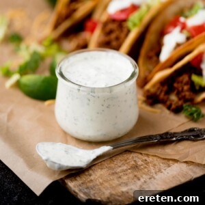 Spoon covered in cilantro lime sauce next to a small glass jar of more of the sauce.