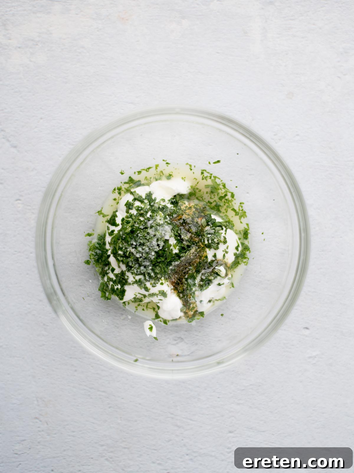 All ingredients for the cilantro lime sauce, including sour cream, chopped cilantro, lime juice, honey, and salt, are added to a small mixing bowl, ready to be combined.
