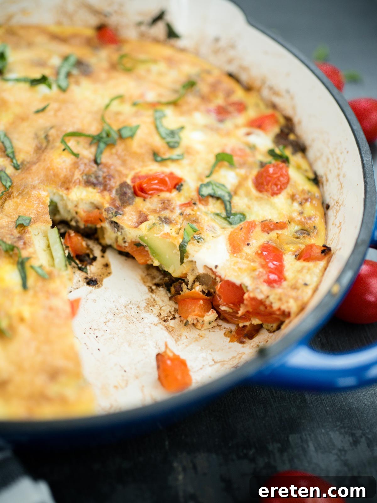 A slice of hearty Veggie, Turkey Sausage, and Basil Frittata removed from the pan, showcasing its rich ingredients
