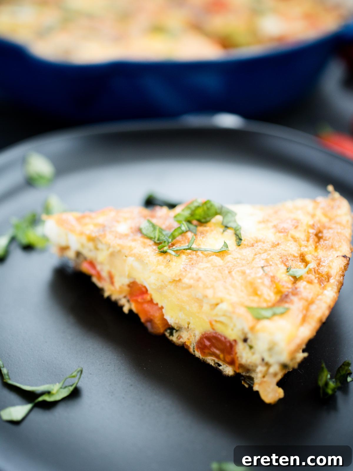 Individual slice of healthy Veggie, Turkey Sausage, and Basil Frittata on a black plate, ready to serve