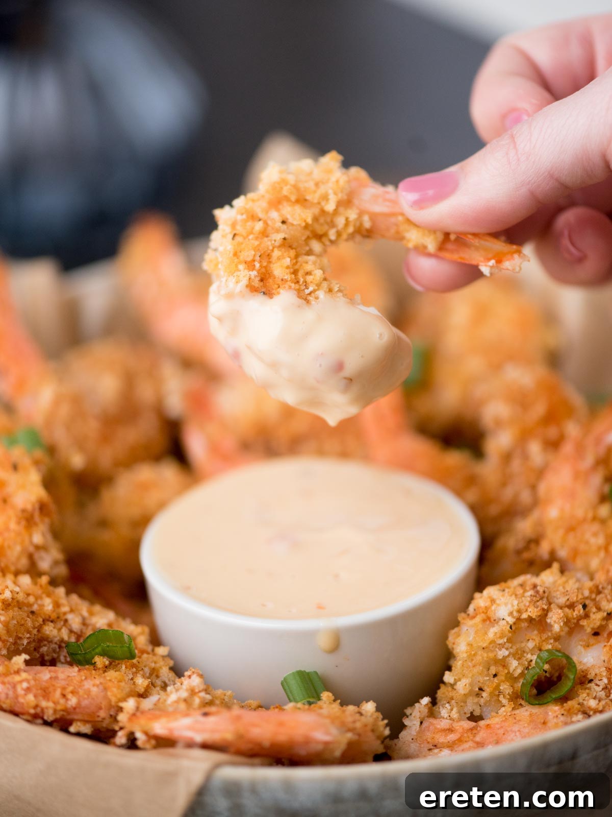 Crispy Baked Bang Bang Shrimp 7 A close-up shot of perfectly crispy, golden-brown shrimp, generously coated in the creamy, vibrant Bang Bang sauce, presented in a small white bowl.