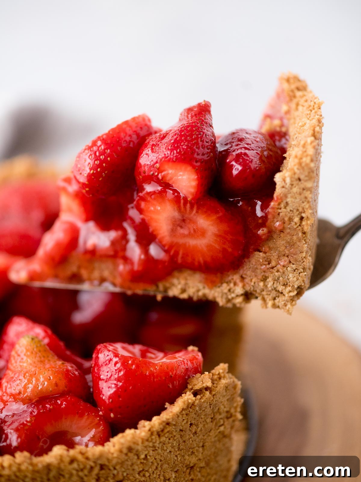 A slice of the fresh strawberry pie being carefully lifted from the main pie, showcasing the thick, fruit-filled layer and crisp crust.