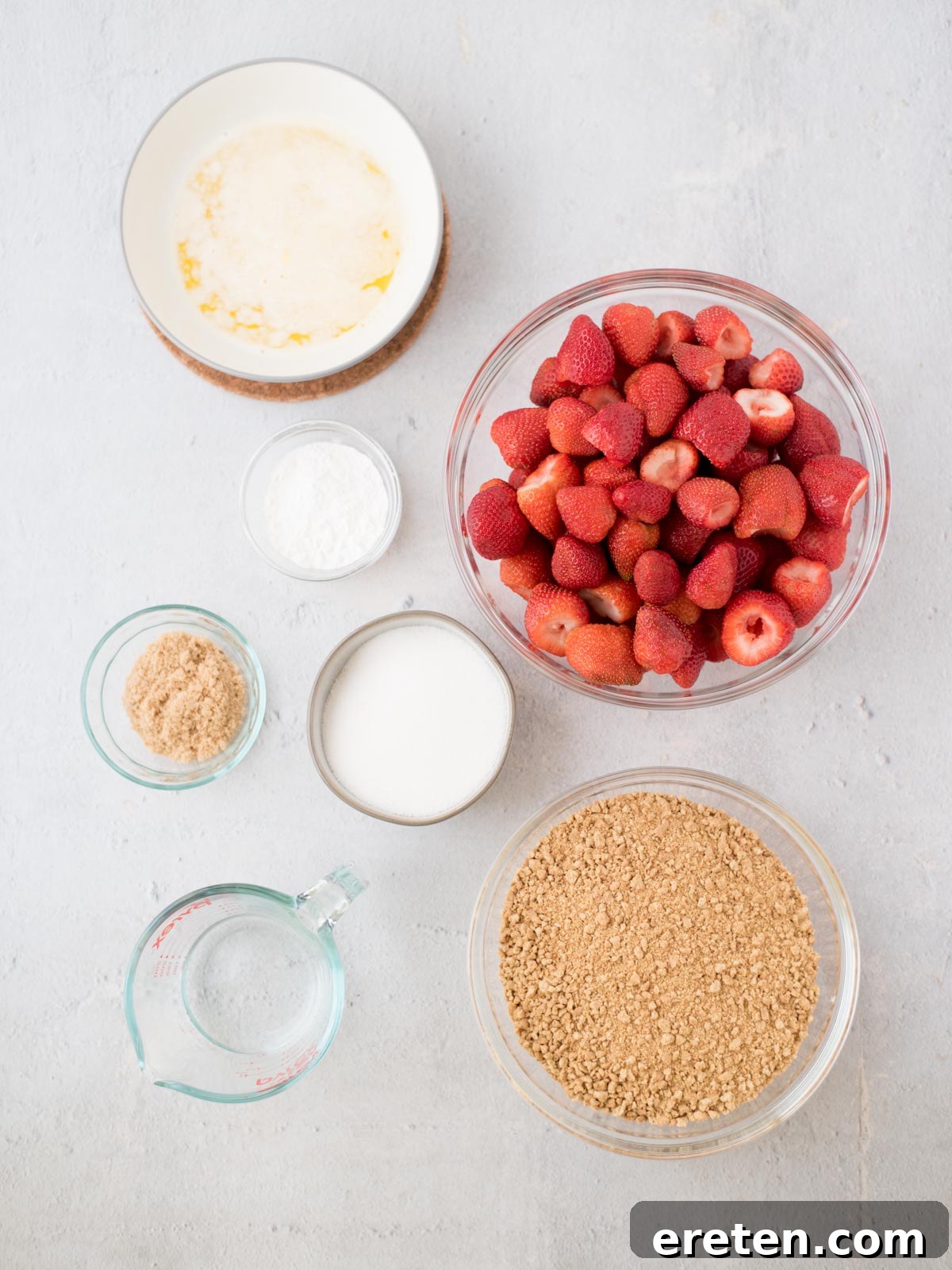 All the fresh ingredients laid out to make a delicious no-bake strawberry pie, including whole strawberries, graham crackers, sugar, cornstarch, and butter.