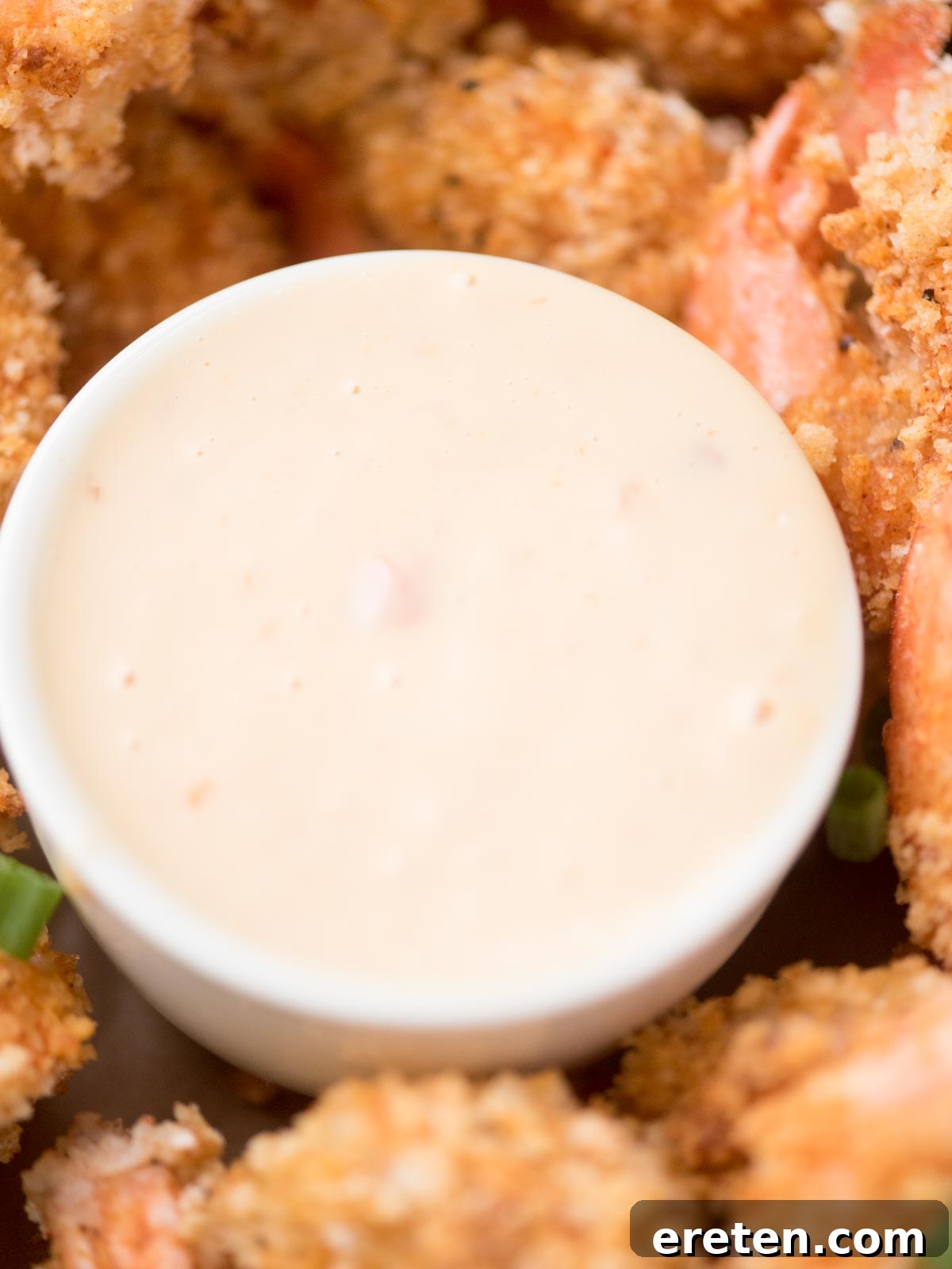 Zing Zing Drizzle 4 Close-up of a creamy dipping sauce in a white bowl surrounded by breaded fried shrimp. The sauce is pale and smooth, while the shrimp are golden brown and crispy, suggesting a savory appetizer or seafood meal.