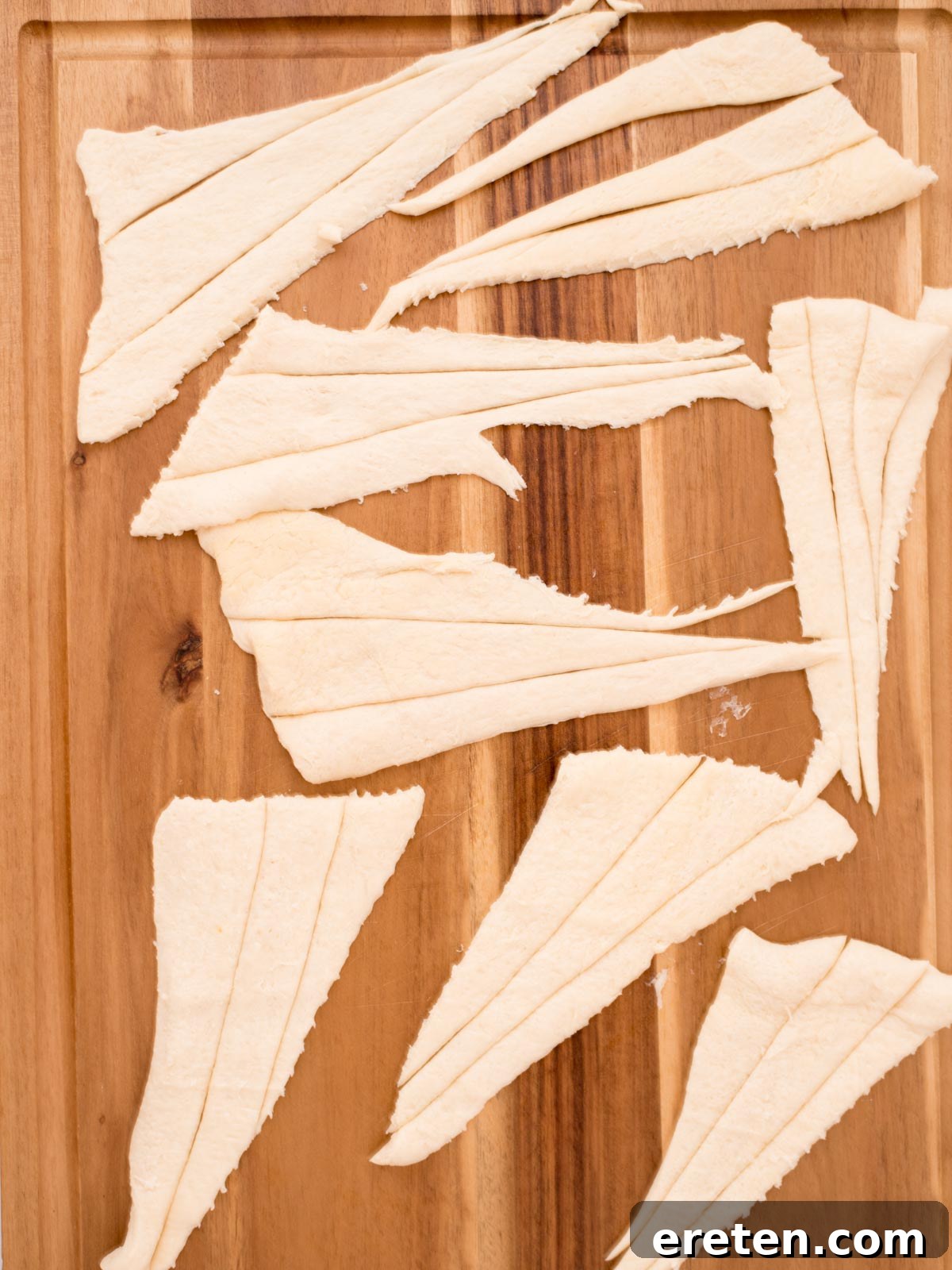 Freshly removed crescent roll dough laid flat on a cutting board, ready for preparation.
