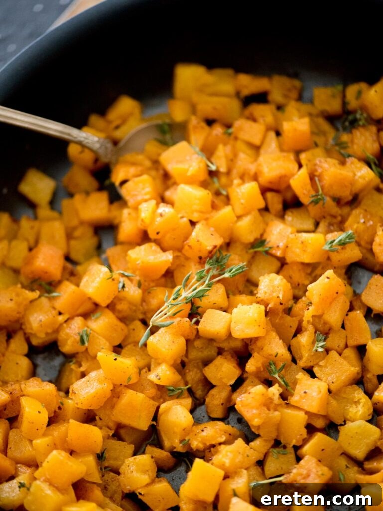 Pan-Seared Butternut Squash Delight 12 A skillet filled with beautifully sautéed butternut squash, generously topped with fresh thyme sprigs, ready to be enjoyed.