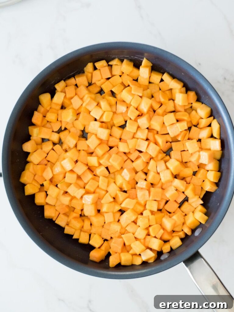 Pan-Seared Butternut Squash Delight 7 Butternut squash cubes thoroughly mixed with melted butter in a skillet, ensuring an even coating.