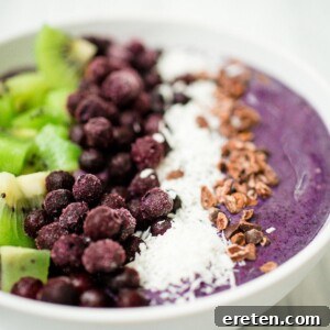 A vibrant and inviting Blueberry Banana Smoothie Bowl, garnished with fresh fruit, coconut, and cacao nibs, ready to be enjoyed.