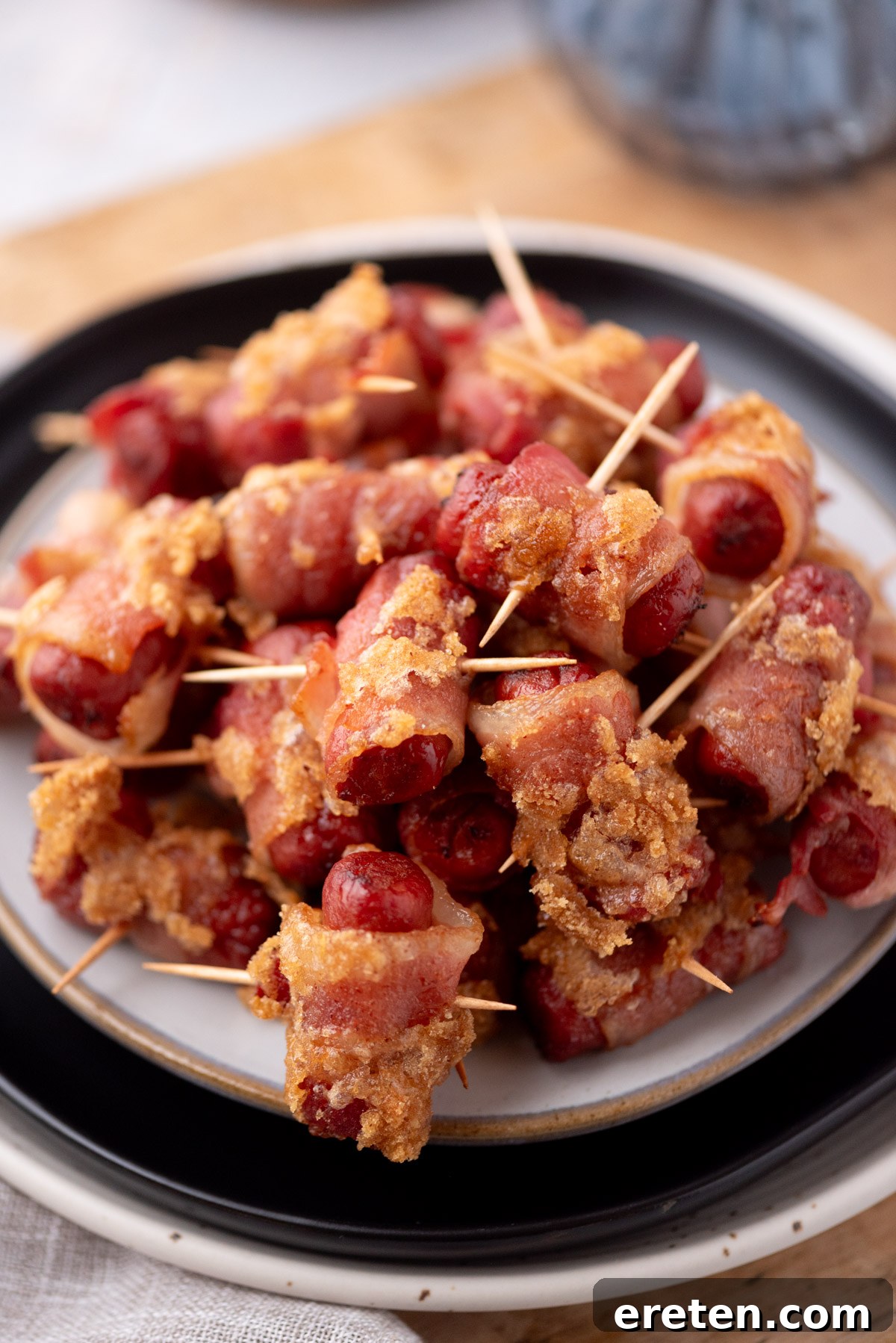Golden Glazed Bacon Bites 6 A plate stacked with bacon wrapped smokies secured with toothpicks, coated in a crispy, golden brown layer, ready to serve as appetizers.