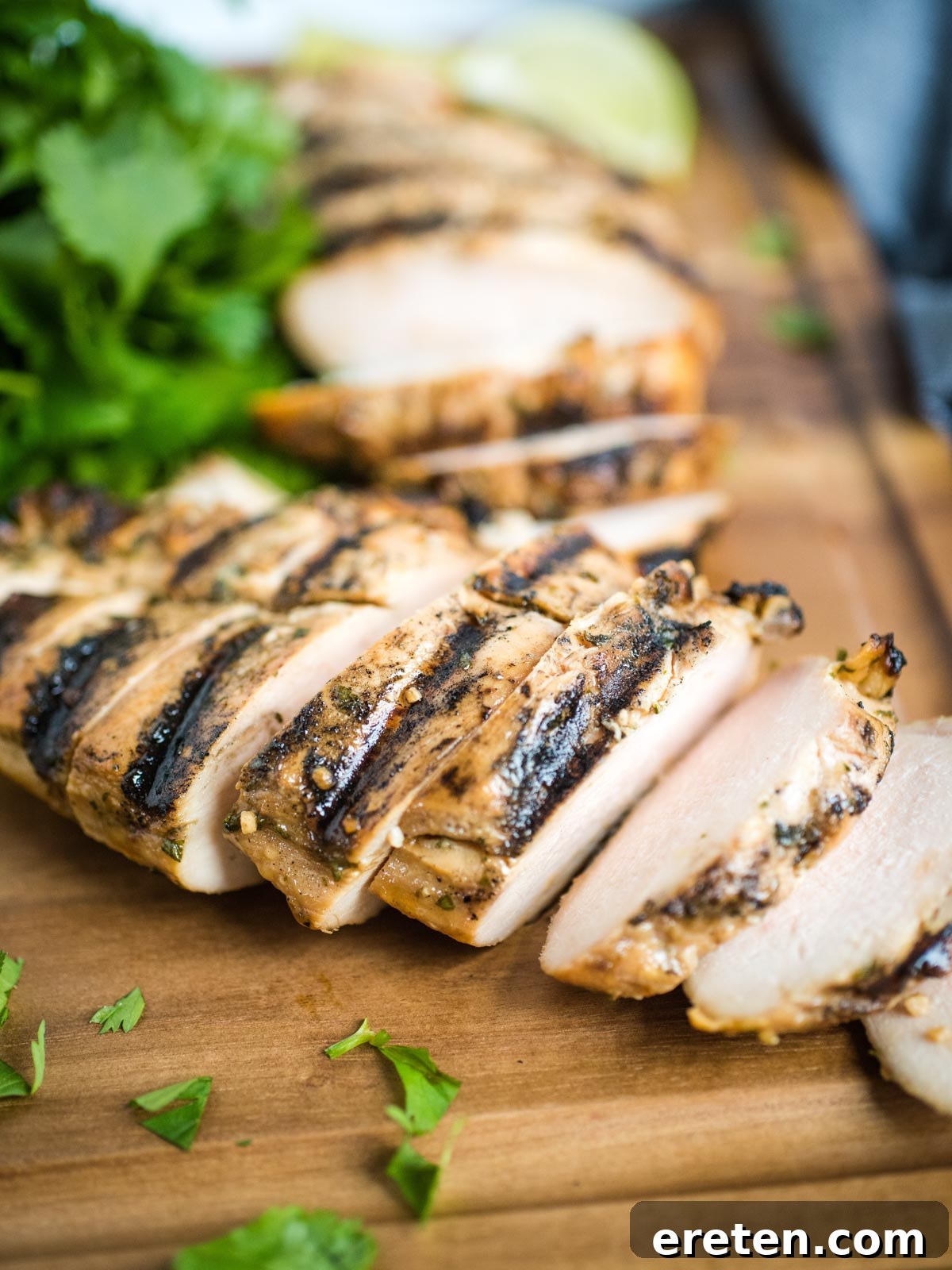 Sliced grilled honey lime chicken on a wooden cutting board, ready to be served.