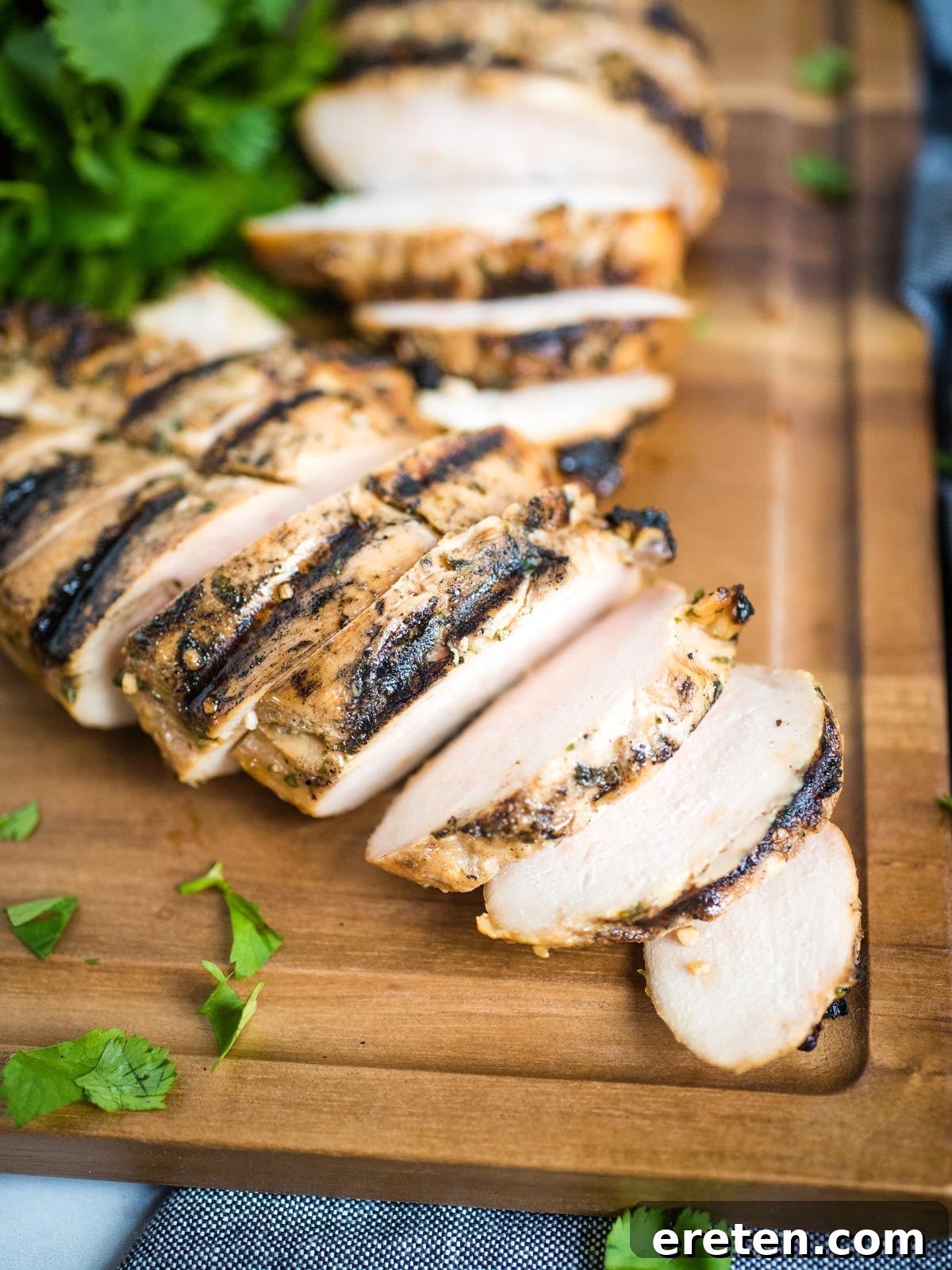 Close-up of perfectly grilled honey lime chicken slices on a cutting board, showcasing its juicy texture.