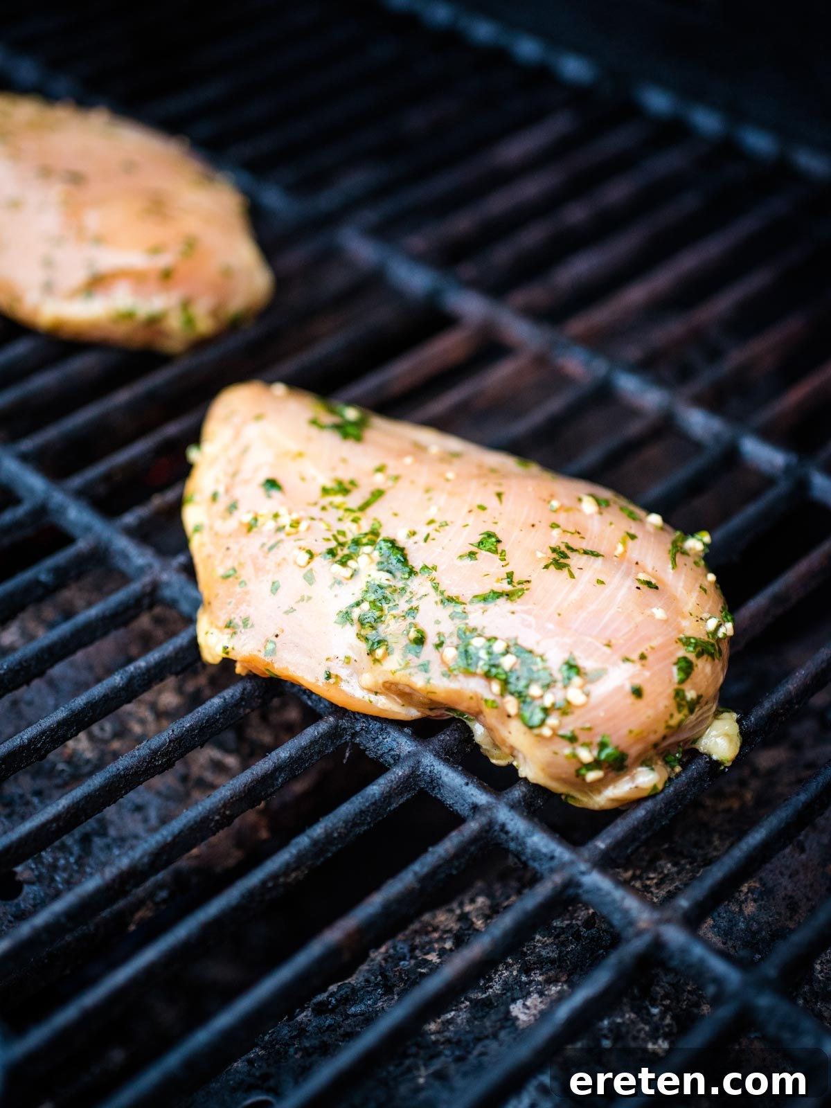 Seasoned marinated chicken cooking on the grill, showing a slight char.