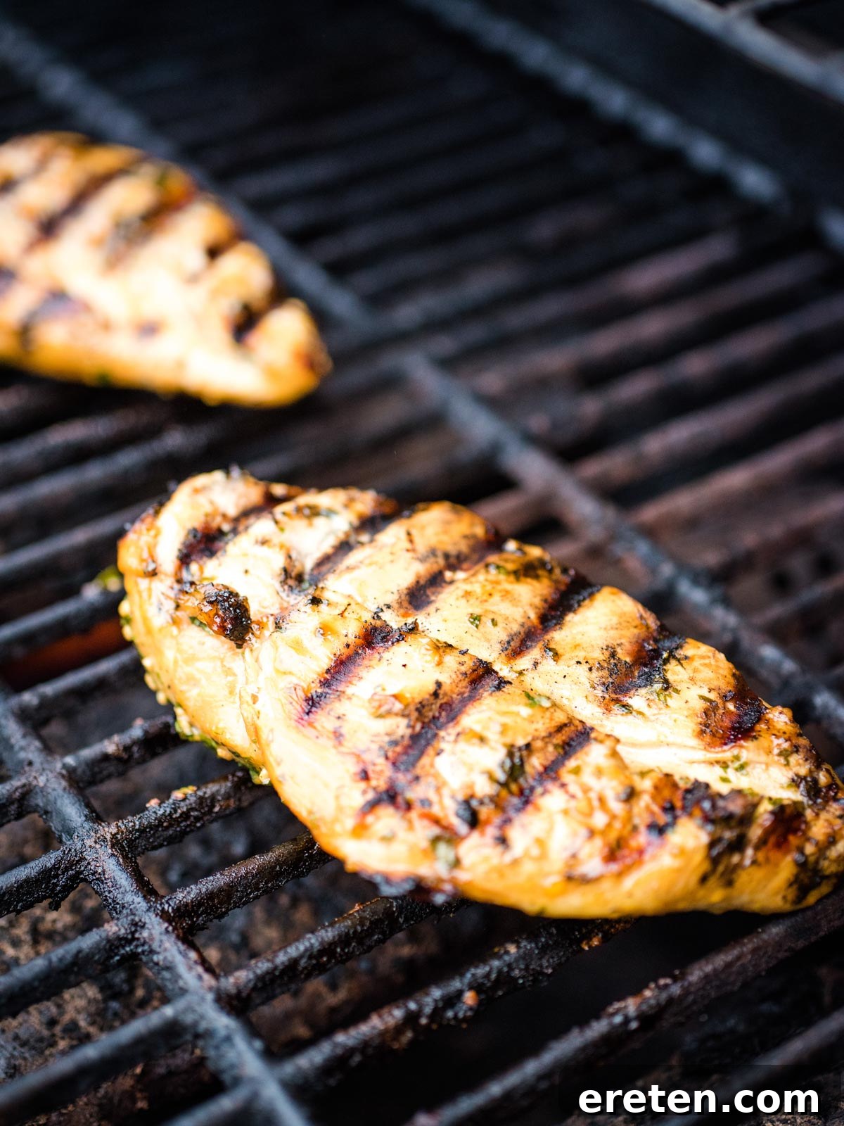 Cooked chicken breasts on the grill, showing prominent grill marks and golden-brown color.
