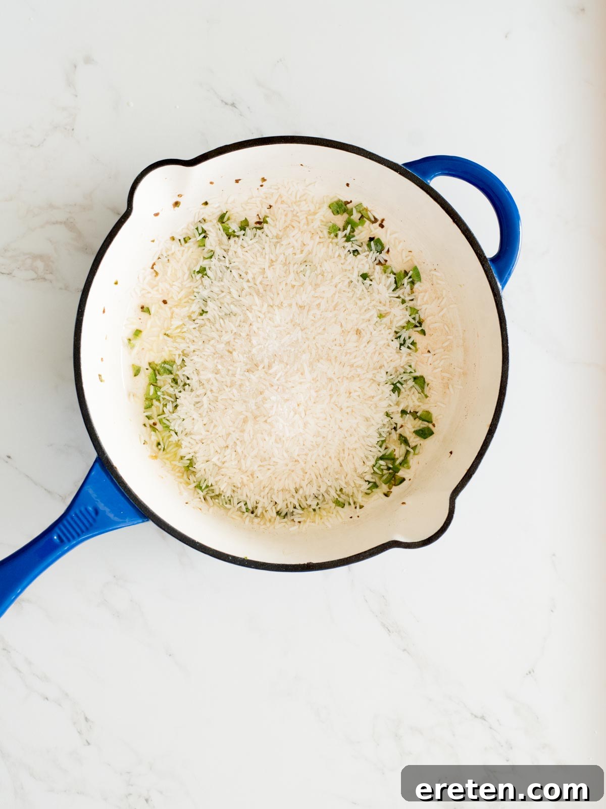 seasoning added to rice in a skillet