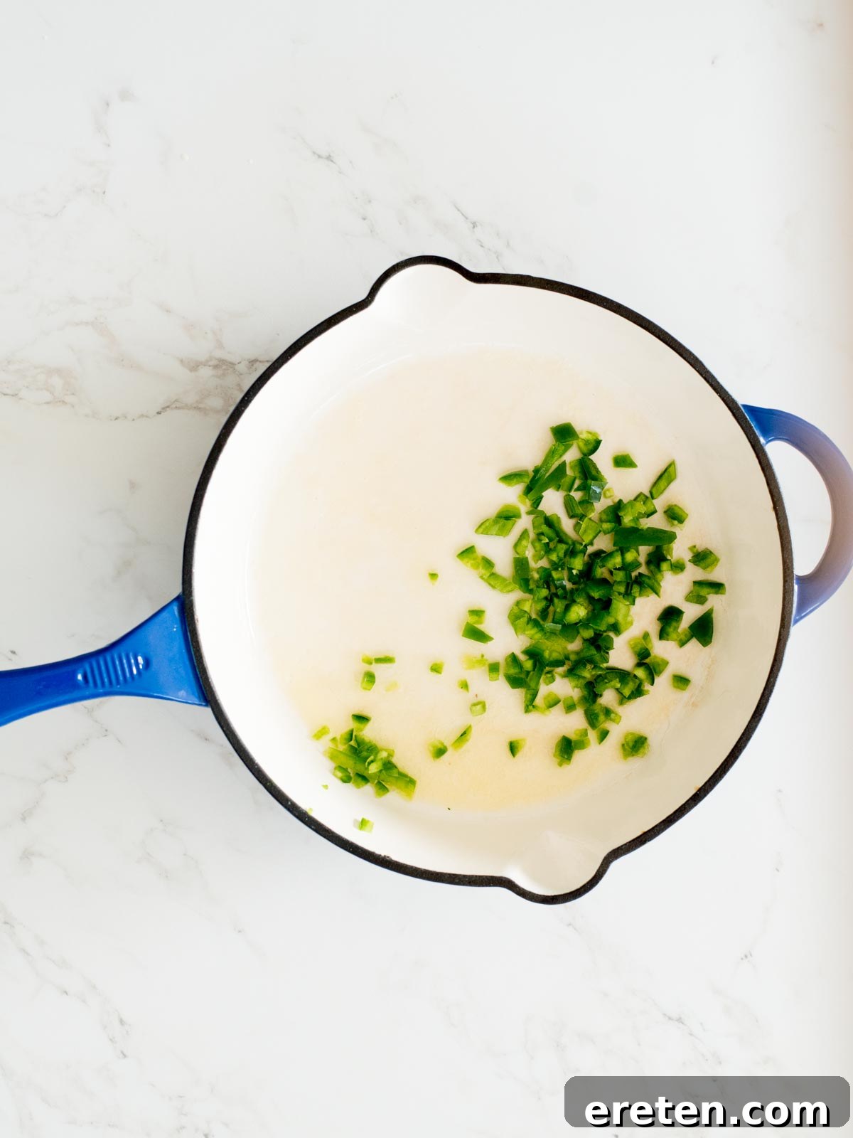chopped jalapeno added to an enamel cast iron skillet with butter
