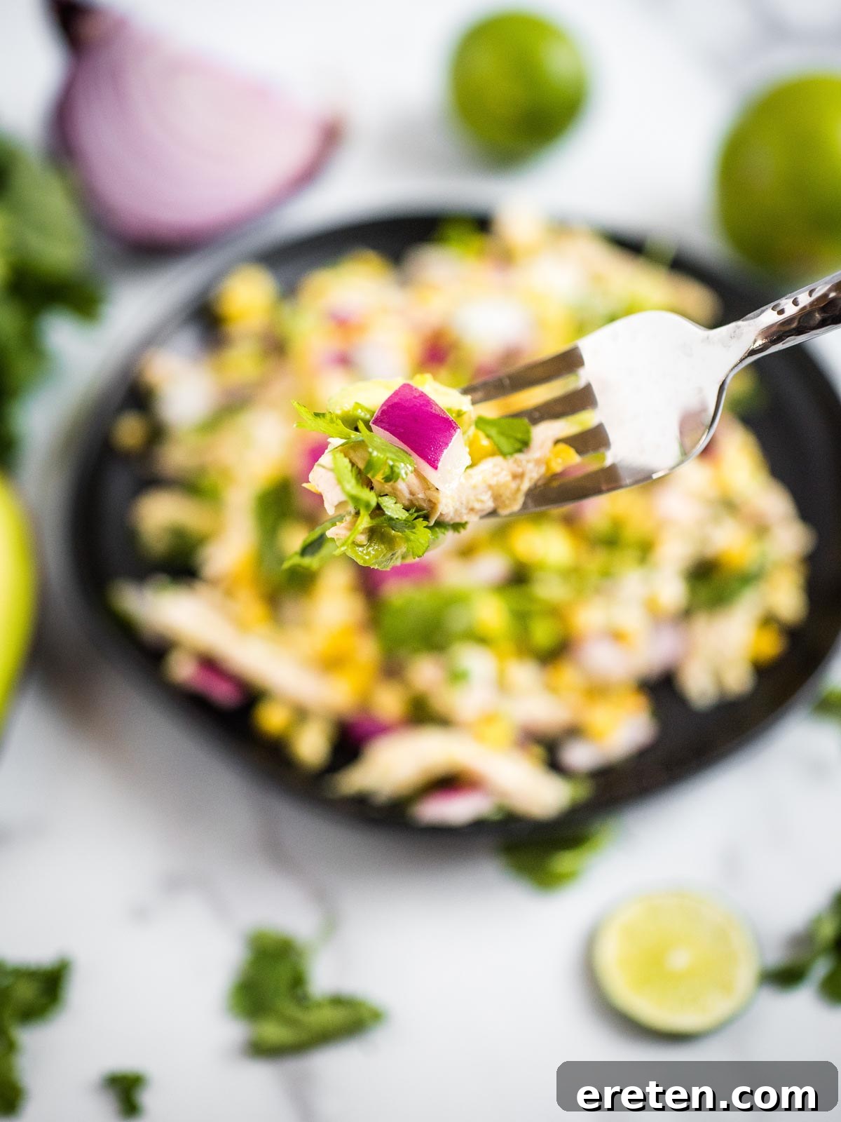A silver fork lifts a perfect bite of Avocado Chicken Chopped Salad, highlighting the fresh textures and colors.