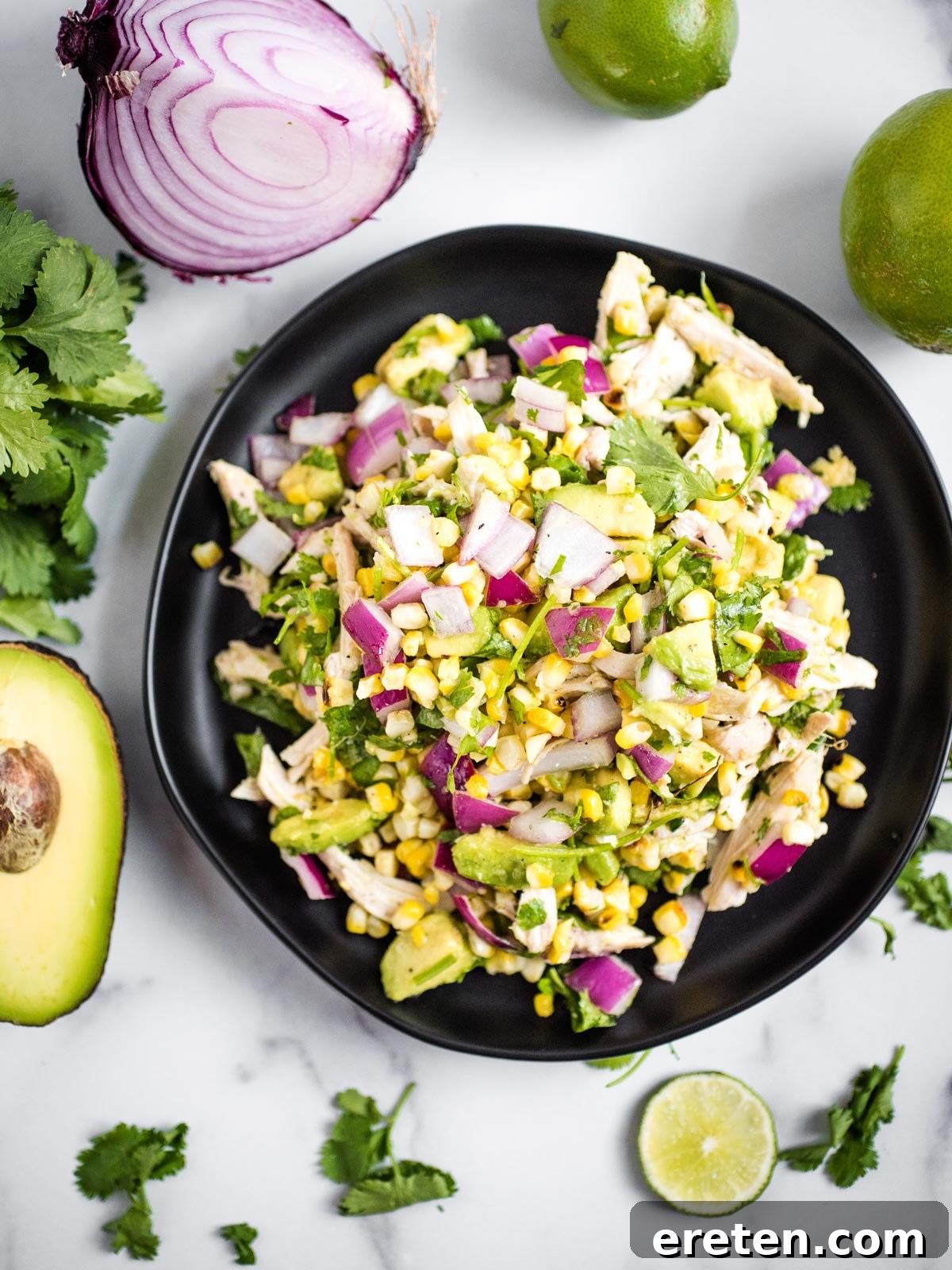 Appetizing close-up of Avocado Chicken Chopped Salad on a black plate, showcasing its freshness.