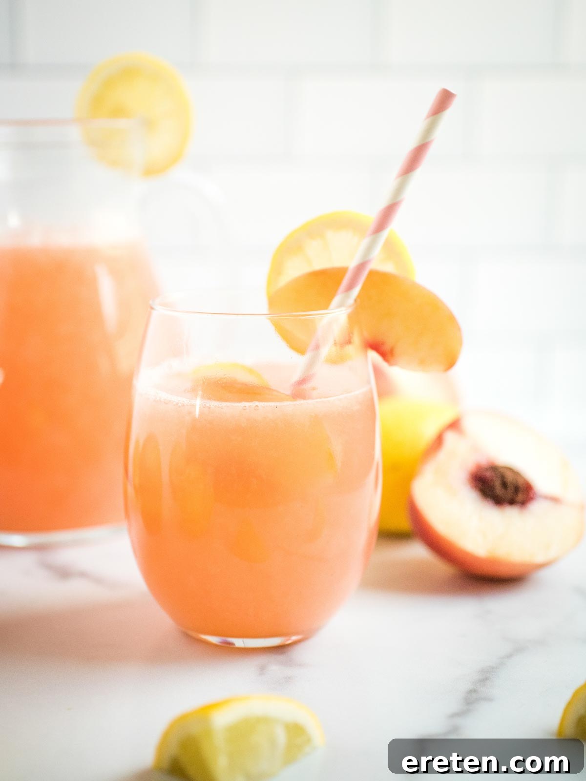 A vibrant glass of homemade peach lemonade with a straw, ready to be enjoyed on a hot day.