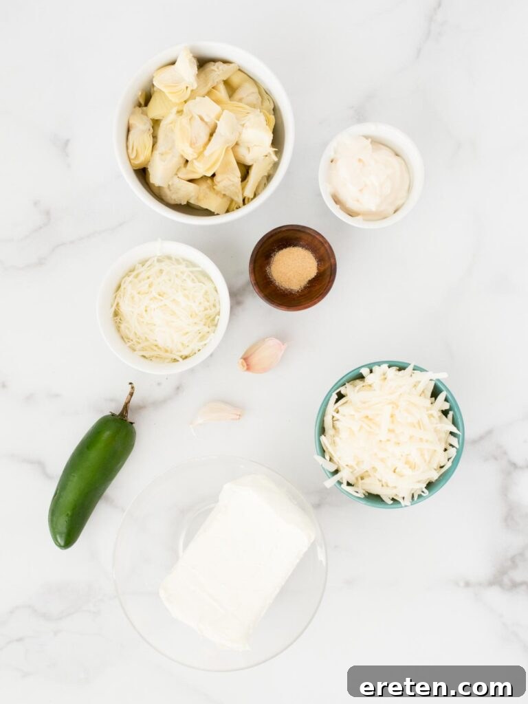 Spicy Artichoke Jalapeno Fusion 3 A selection of ingredients for Jalapeno Artichoke Dip, including cream cheese, mayonnaise, parmesan, garlic, garlic powder, jalapeno, mozzarella, and artichoke hearts, laid out on a white surface.