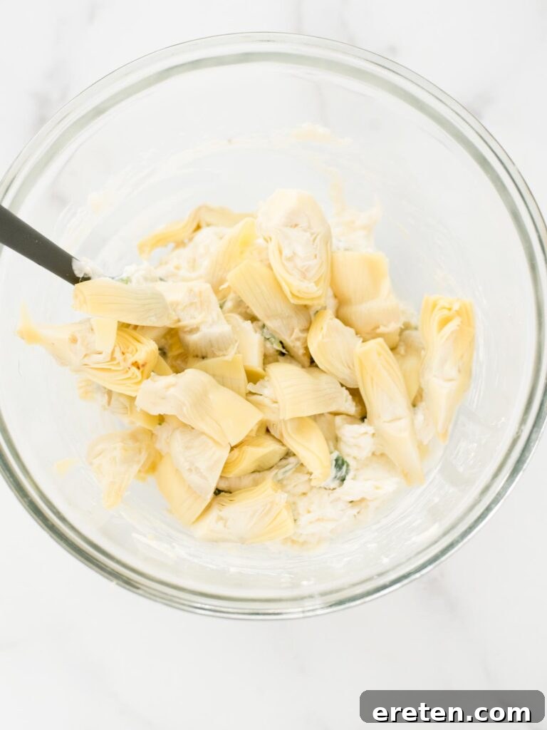 Spicy Artichoke Jalapeno Fusion 10 Chopped artichoke hearts being gently folded into the mixed dip ingredients.