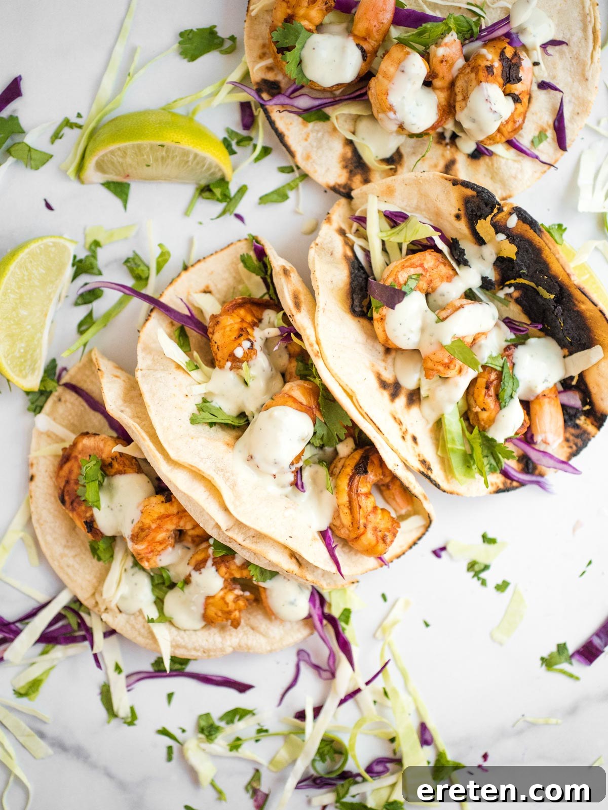 Overhead shot of vibrant chili lime shrimp tacos with fresh cilantro and lime wedges