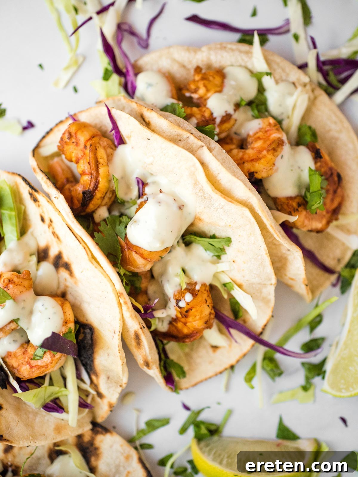 Overhead shot of two chili lime shrimp tacos with dressing and cilantro
