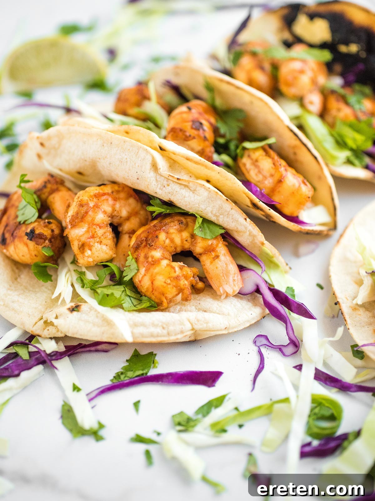 Side shot of three chili lime shrimp tacos on a plate