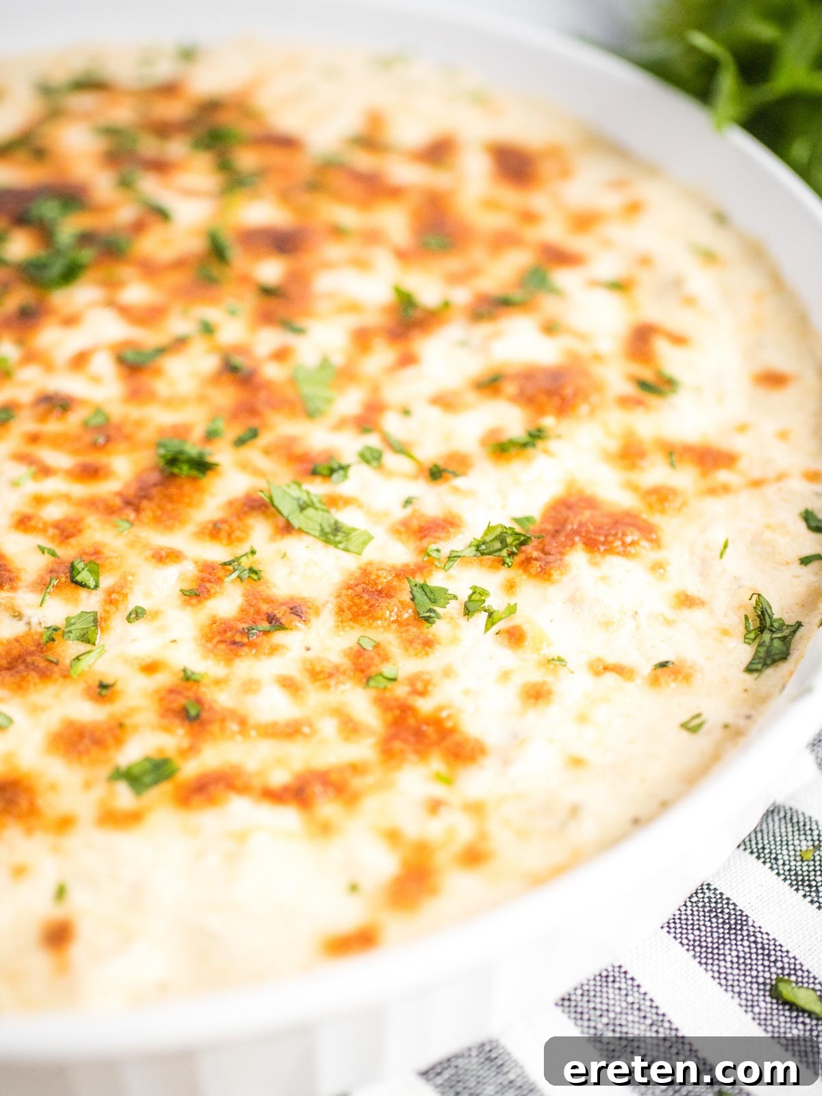 A close-up shot of a vibrant green chile queso blanco dip in a white dish, showcasing its creamy texture and delicious components.