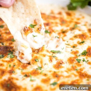 chip dipping into green chile queso blanco dip