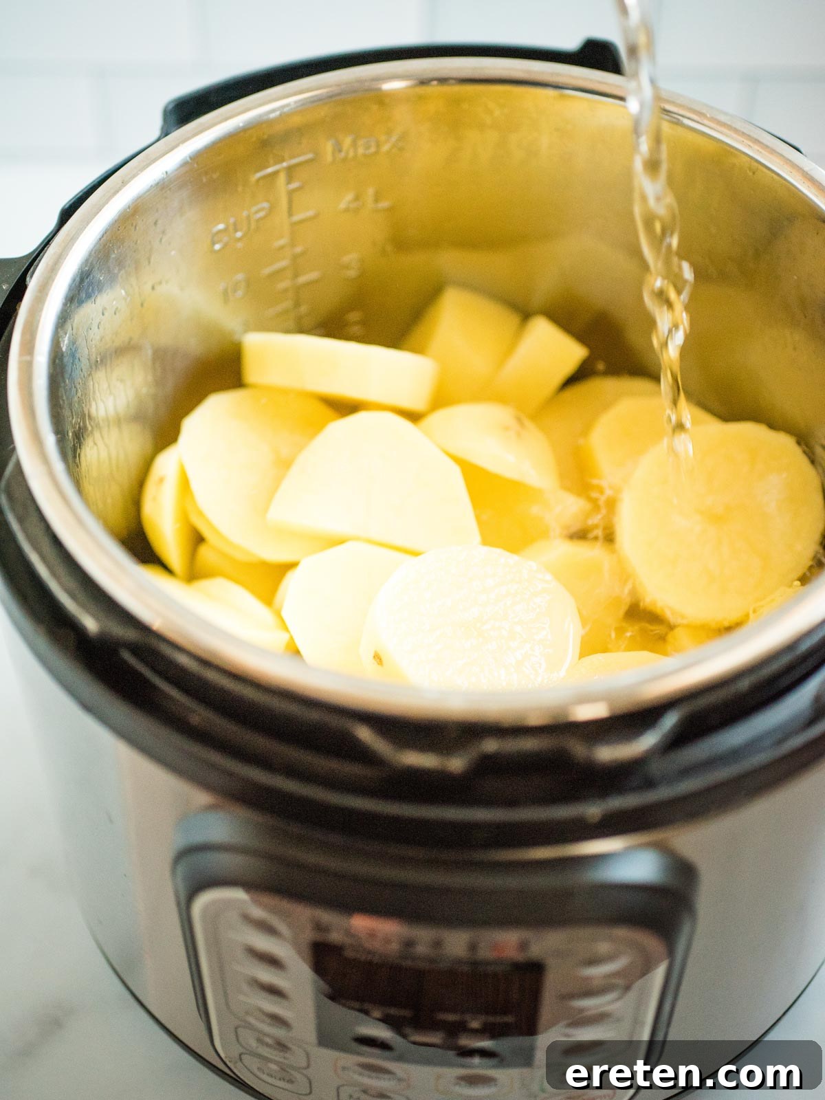 Sliced potatoes in an Instant Pot with water pouring over them
