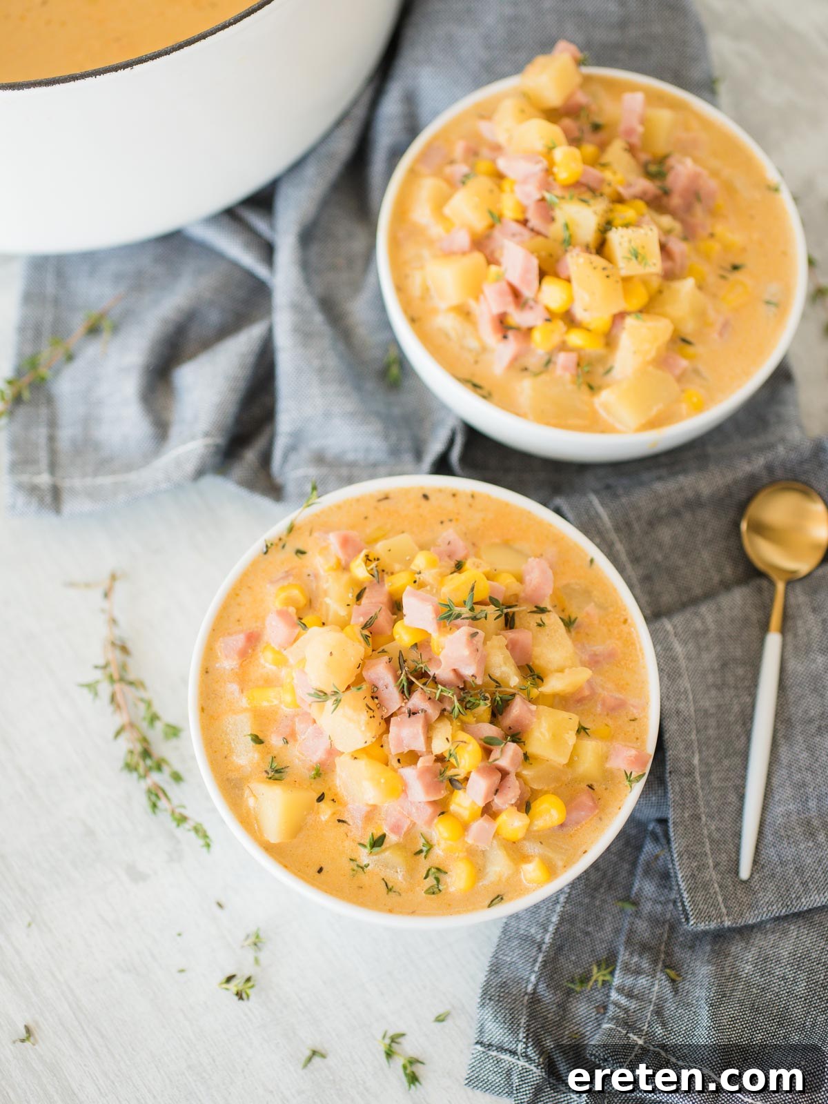 Two rustic bowls filled with hearty creamy ham and potato corn chowder, inviting a comforting meal.