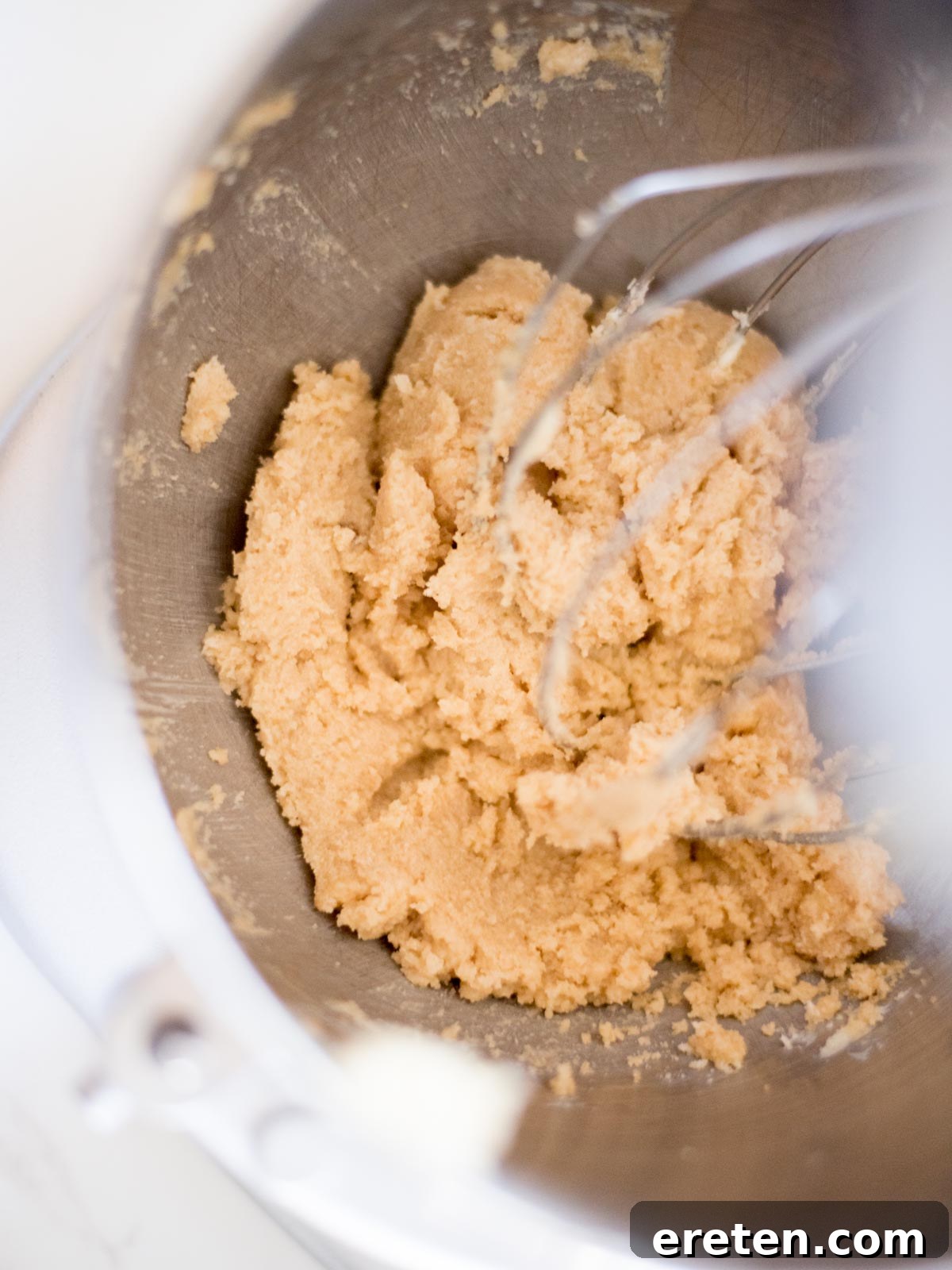 Softened butter, brown sugar, and white sugar creamed together in a metal mixing bowl, forming a light mixture