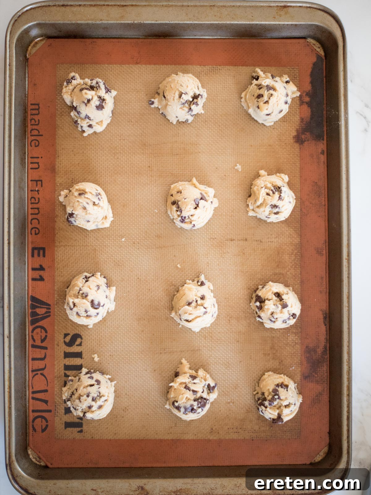 Perfectly scooped balls of chewy chocolate chip cookie dough arranged on a baking sheet, prepped for baking