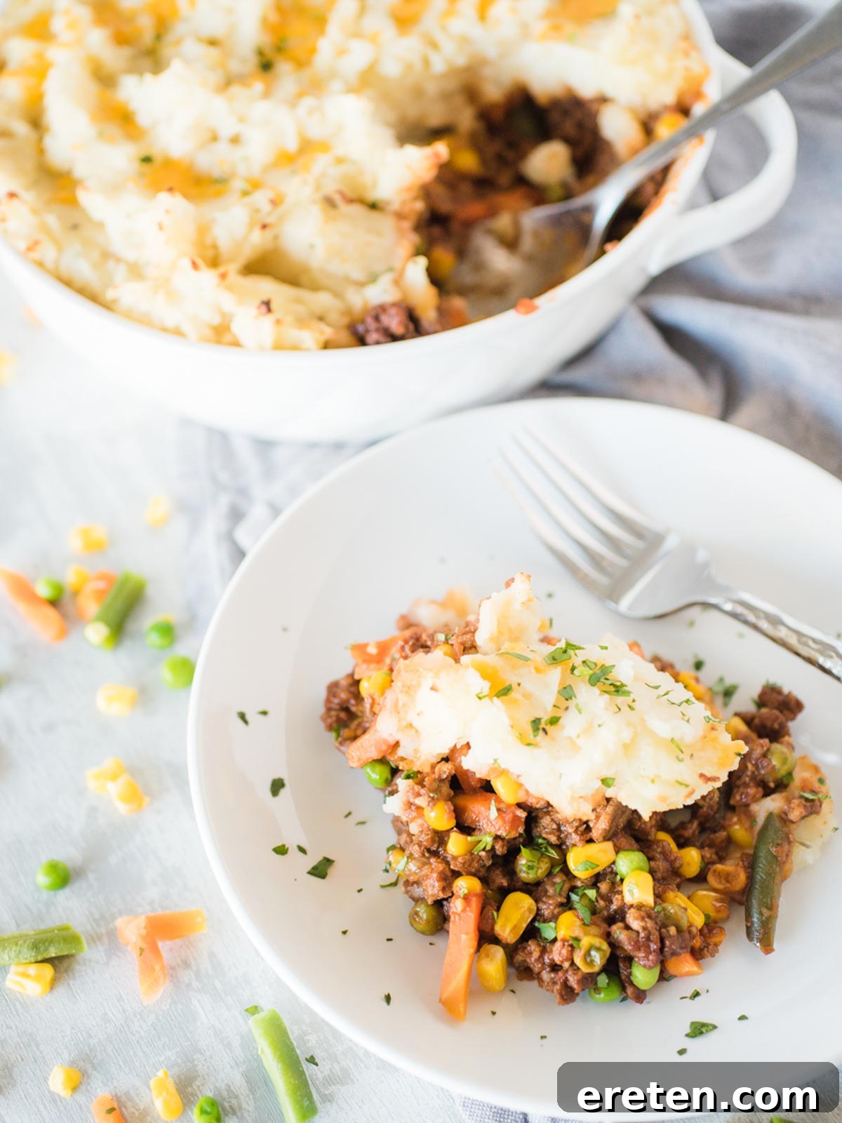 A delicious serving of Shepherd's Pie in a white shallow bowl, topped with golden mashed potatoes.