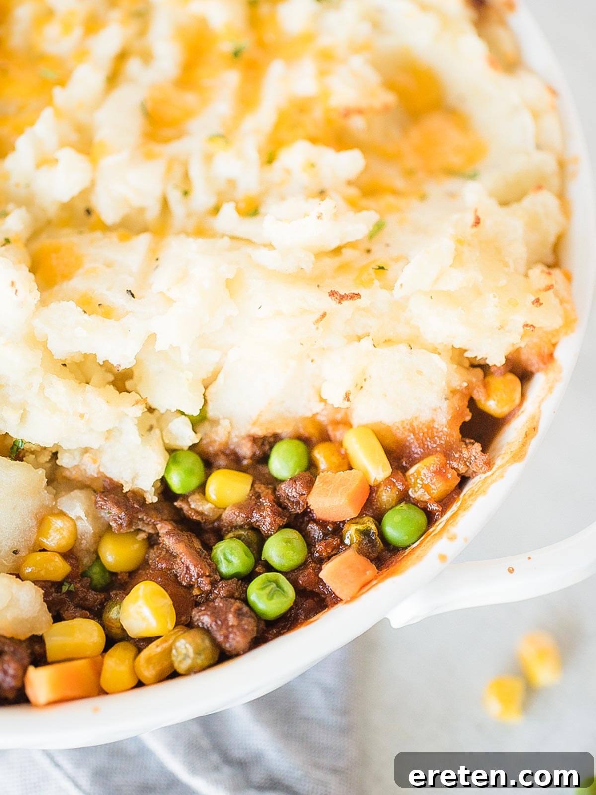 A close-up view of the inside of a Shepherd's Pie in a white baking dish, showing the layers of meat and mashed potato.