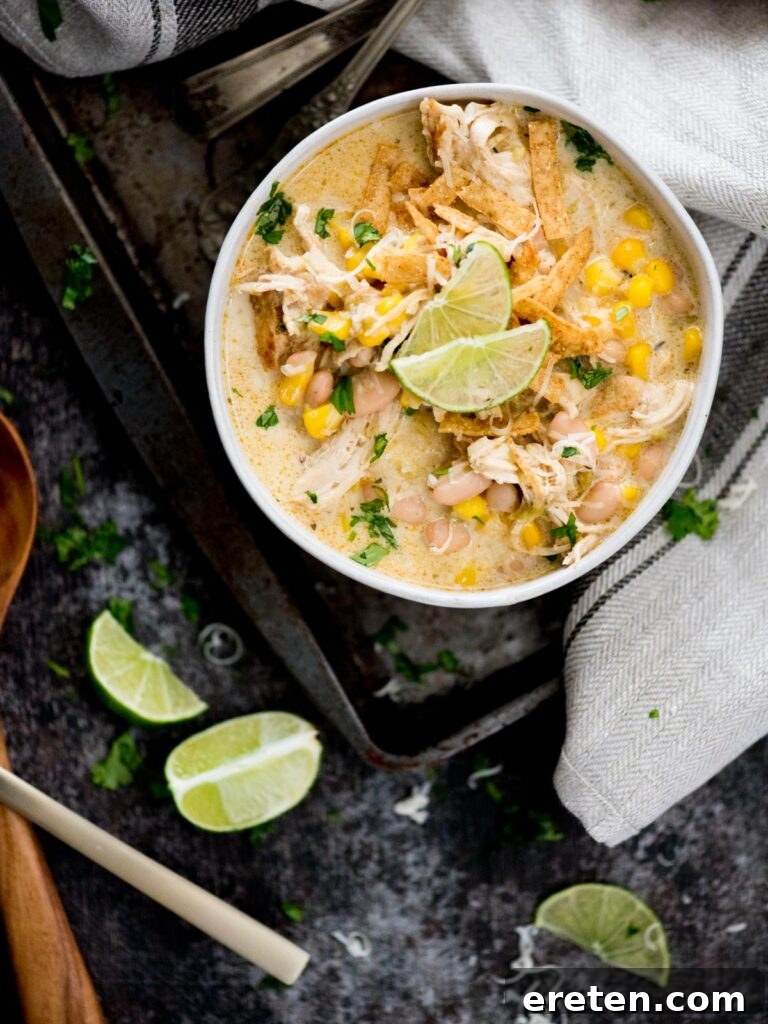A vibrant bowl of creamy Instant Pot White Chicken Chili, garnished with shredded cheese, crispy tortilla strips, and a fresh lime wedge, ready to be enjoyed.