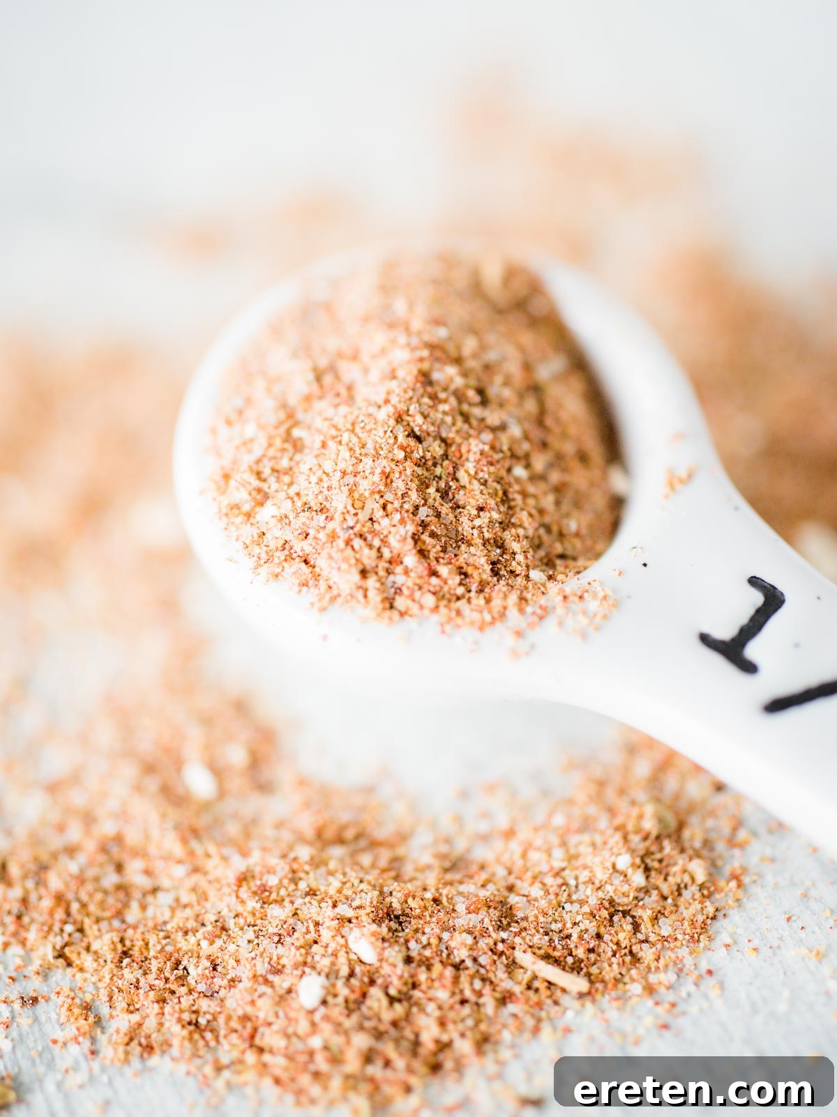 Homemade Mild Taco Spice Blend 4 A pile of homemade taco seasoning on a kitchen counter with a small measuring spoon nestled in it.