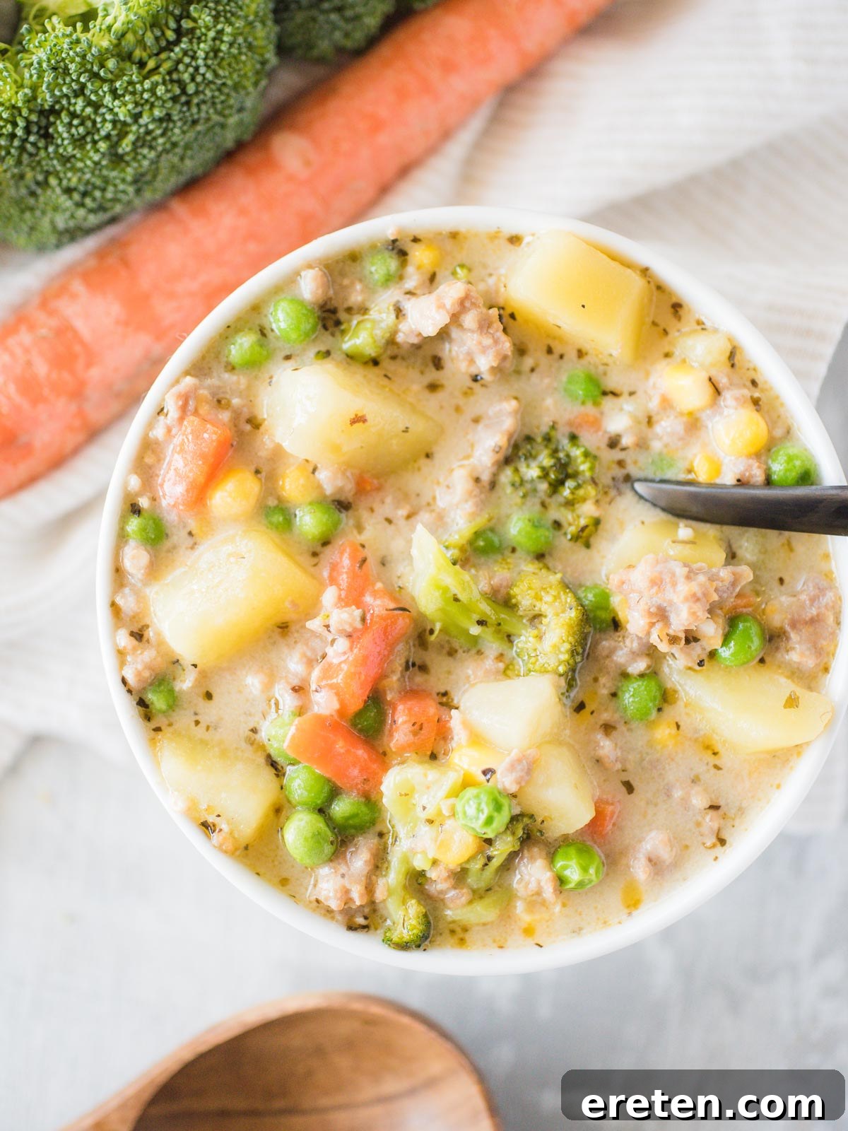 A bowl of creamy Cheesy Italian Sausage Potato Soup with a black spoon, garnished with fresh parsley.
