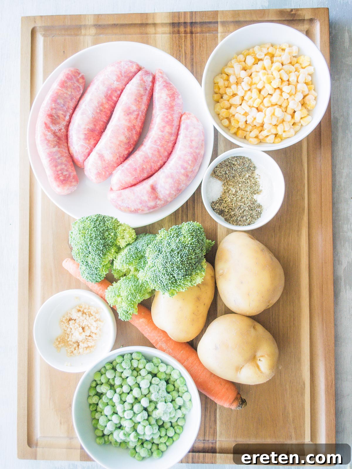 Fresh ingredients laid out for Cheesy Italian Sausage Potato Soup, including sausage, potatoes, carrots, and herbs.