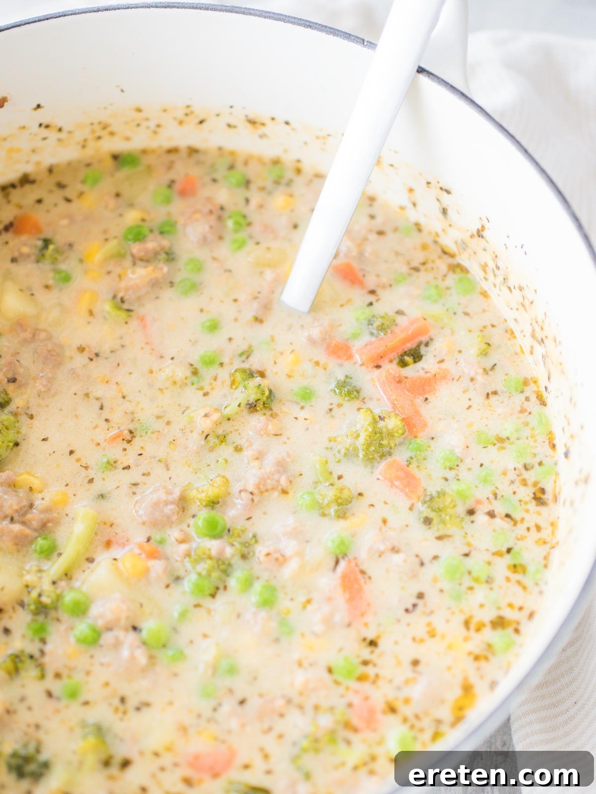 A large pot of simmering Cheesy Italian Sausage Potato Soup, ready to be served.