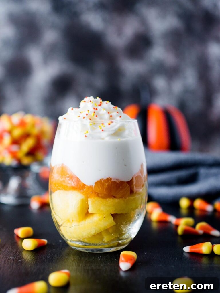 Vibrant Candy Corn Inspired Fruit Parfait in a glass, surrounded by candy corn pieces, perfect for Halloween