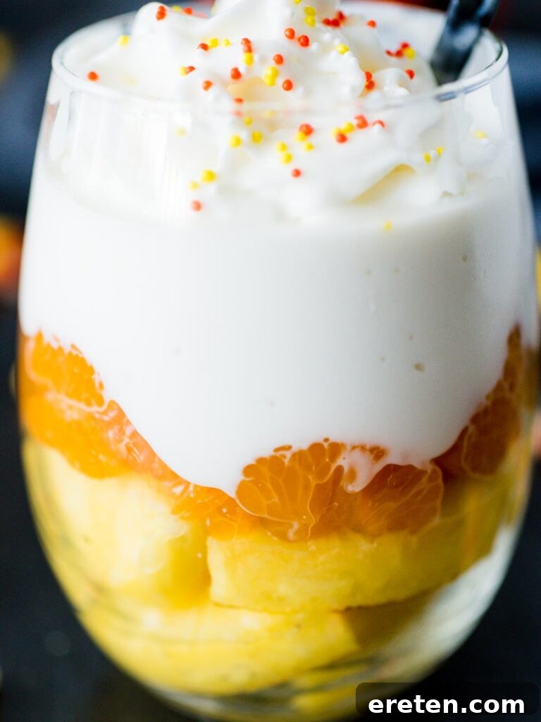 Close-up of a perfectly layered Candy Corn Inspired Fruit Parfait in a glass, showcasing the yellow, orange, and white layers