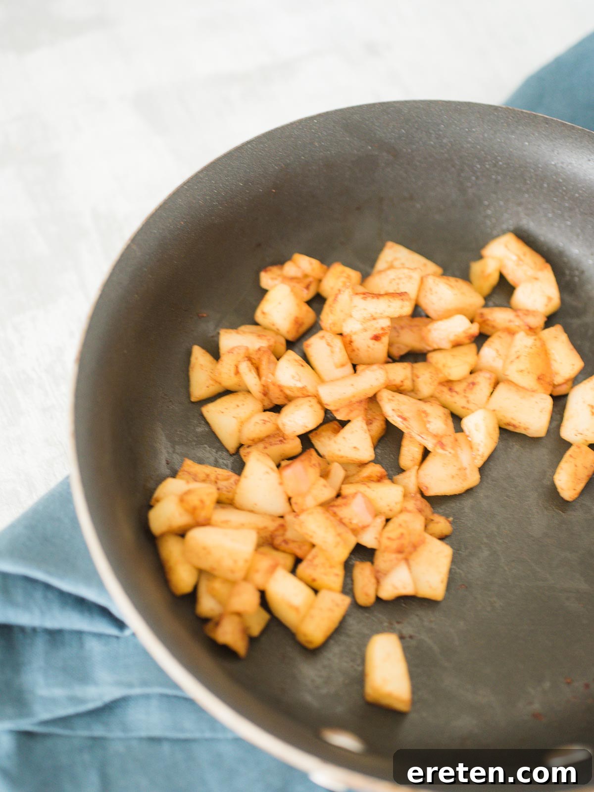 Diced apples cooking in a pan with maple syrup and cinnamon