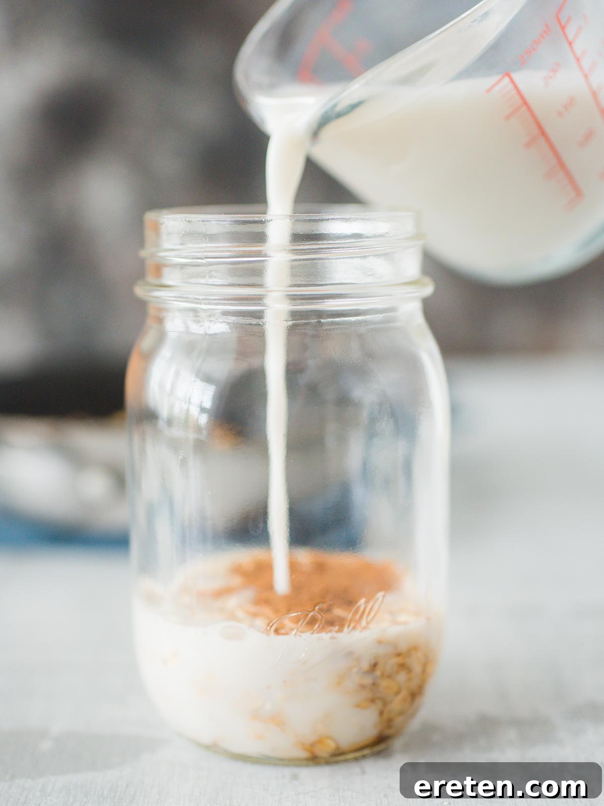 Almond milk being poured into a jar with oats