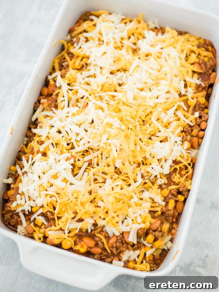 Kickin Tex Mex Lasagna 12 An unbaked Tex Mex lasagna in a casserole dish, ready for the oven, topped with cheese.