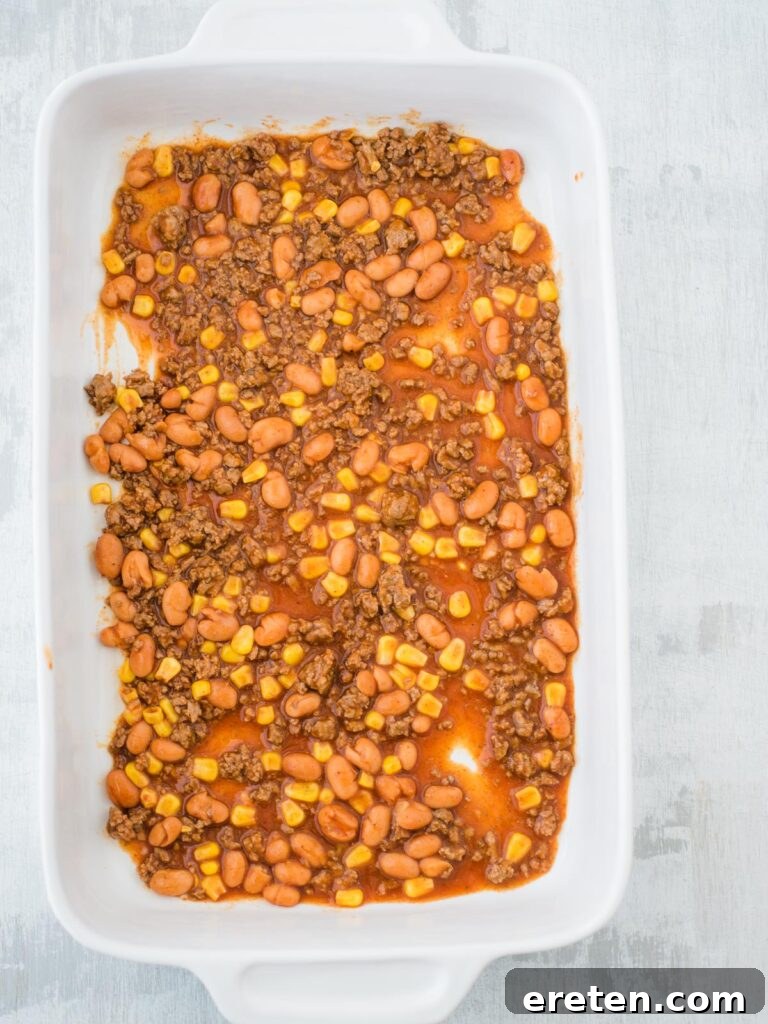 Kickin Tex Mex Lasagna 4 A thin layer of savory enchilada sauce coats the bottom of a casserole dish, ready for lasagna layering.