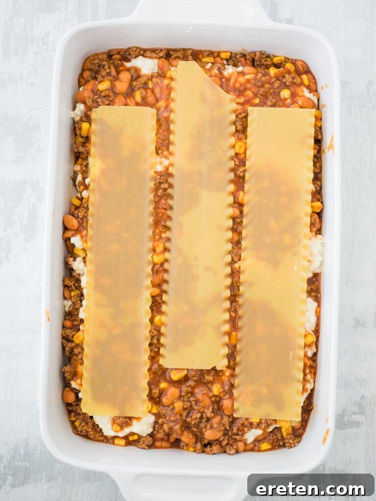 Kickin Tex Mex Lasagna 10 The final layer of uncooked lasagna noodles being placed, completing the pasta base.