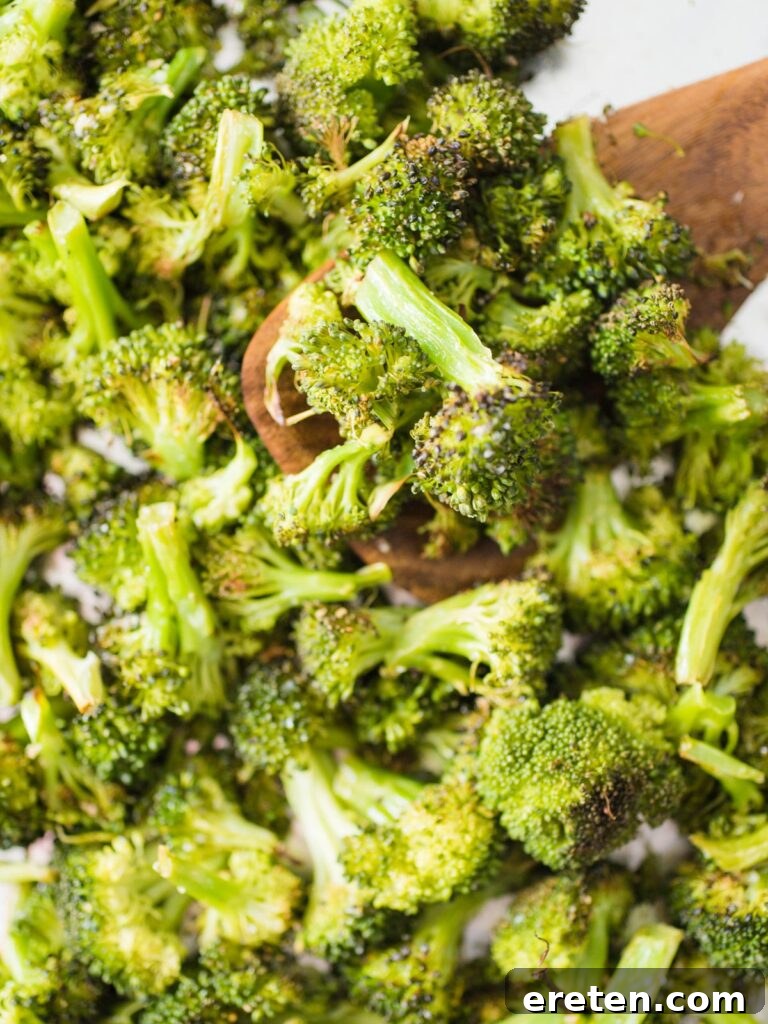 Crispy Oven Roasted Broccoli 2 Perfectly roasted broccoli on a baking sheet, golden and slightly charred at the edges.