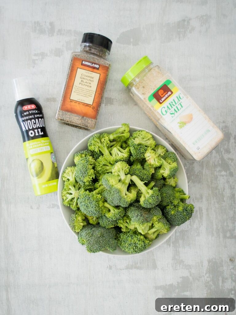 Crispy Oven Roasted Broccoli 3 Close-up of fresh broccoli florets, avocado oil spray, garlic salt, and black pepper, ready for roasting.