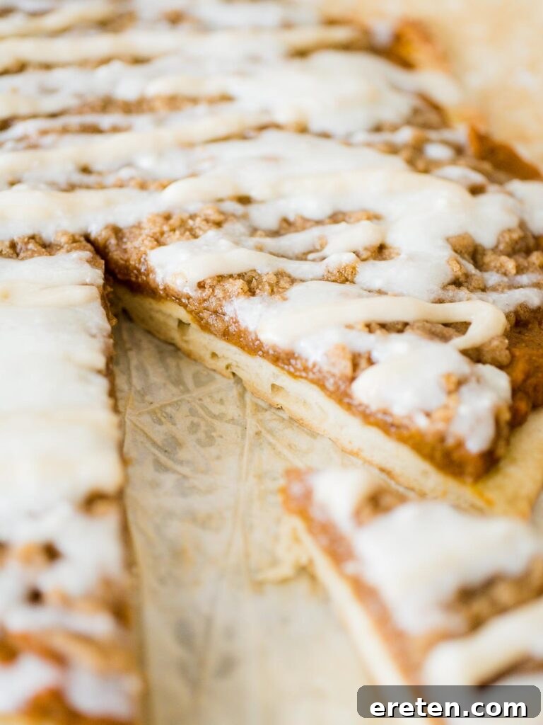 Sweet Pizza Creations: A Homemade Guide 7 A close-up view of a slice of Pumpkin Dessert Pizza, showing the layers of crust, pumpkin filling, streusel, and cream cheese drizzle.